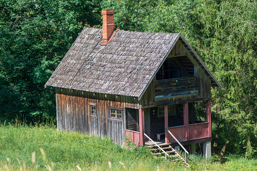 Old wooden vintage house in a clearing with green grass.