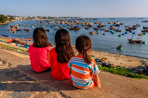 Vietnamese children looking at fishermen's boats  in a harbour, Vietnam