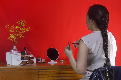 Woman Doting Make-Up on the Red Background//Studio Shot
