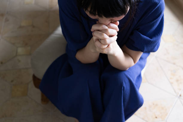 A woman anxiously folds her hands.\nA woman praying with folded hands. Prayer.\nTaken from above. Overhead view.