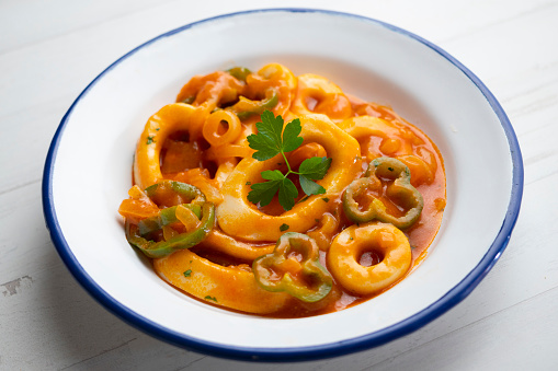 Pasta with Clams, mussels, calamari, shrimps, and cherry tomatoes in marinara sauce on white background