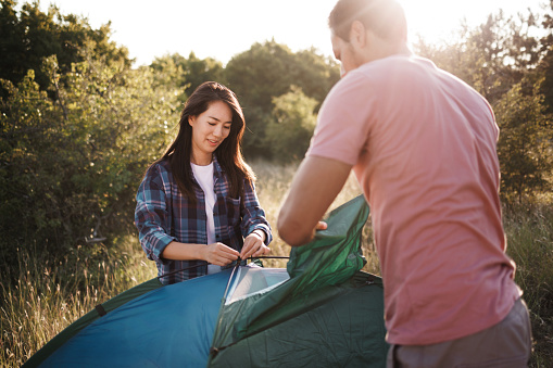 Couple setting up tent outdoors in a forest
