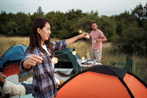Couple decorating camping tents with string lights