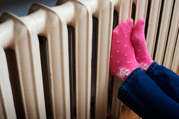 istock Female warming up her feet on central heating radiator 1707936394