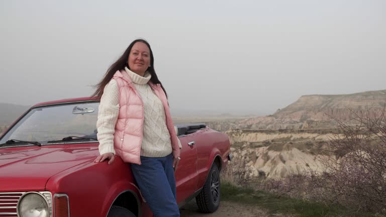 Smiling woman enjoying landscape while standing by car