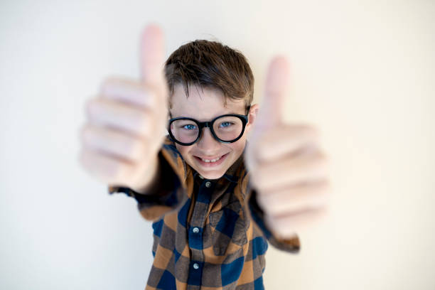 cool young boy wearing black glasses in front of brown background