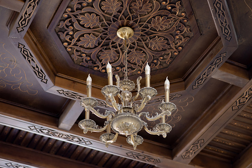 Ancient chandelier on wooden carving ceiling background
