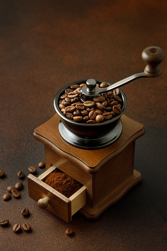 wooden manual grinder with coffee beans on the brown table