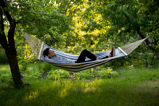 young man lying in the hammock on the summer vacation tour, relaxation outdoors