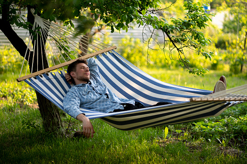 young man lying in the hammock on the summer vacation tour, relaxation outdoors