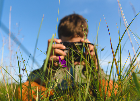Boy shooting flowers in meadow