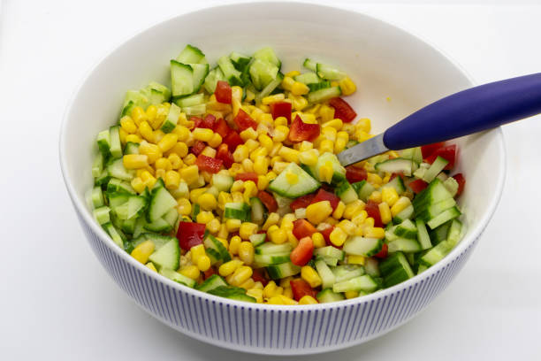 Salad in bowl with cucumber red bell pepper and corn isolated on white