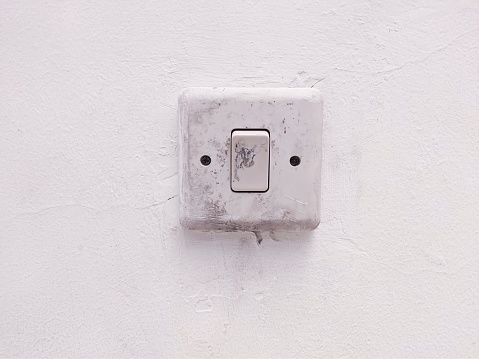 An old single light switch on white wall