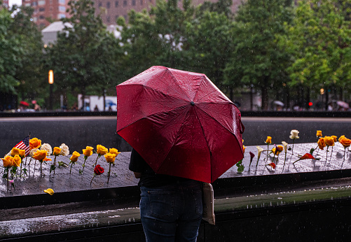 New York, USA - September 12, 2023: Pedestrians using umbrellas to shelter from the rain as they walk near the ground zero in downtown New York City, NY, USA