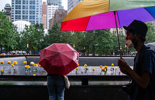 New York, USA - September 12, 2023: Pedestrians using umbrellas to shelter from the rain as they walk near the ground zero in downtown New York City, NY, USA
