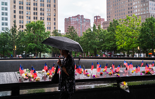 New York, USA - September 12, 2023: Pedestrians using umbrellas to shelter from the rain as they walk near the ground zero in downtown New York City, NY, USA