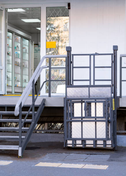 Wheelchair platform lift for disabled access at the entrance to a pharmacy Grey wheelchair platform lift for disabled access near the stairs at the entrance to a pharmacy. wheelchair lift stock pictures, royalty-free photos & images