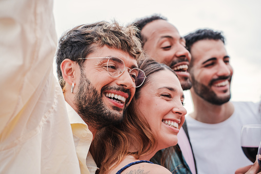 Meeting of smiling group of people celebrating a party, having fun and enjoying the moment together. Young cheerful and excited friends, men and women enjoying a festival. Joyful buddies gathering. High quality photo