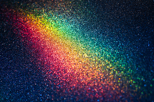 Defocused glitter texture background with rainbow bokeh lights on it.