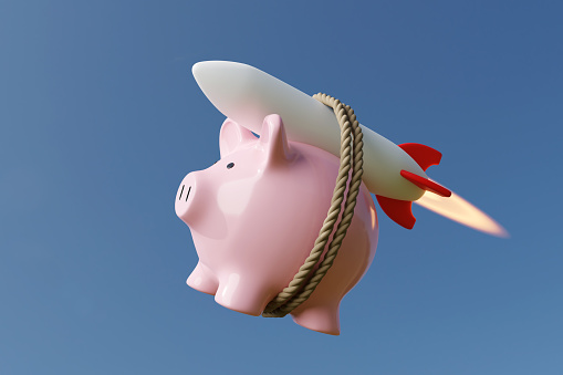 Pink piggy bank carried by a rocket in clear blue sky. Illustration of the concept of skyrocketing prices of stocks and other investment