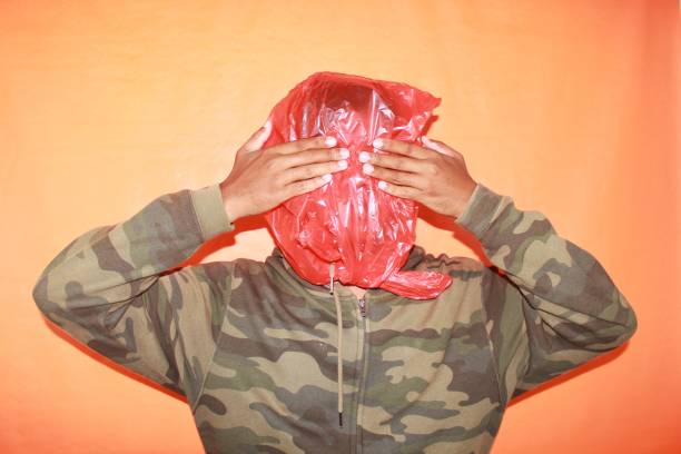 face of mature asian man wrapped in plastic with both hands posing in front of the camera