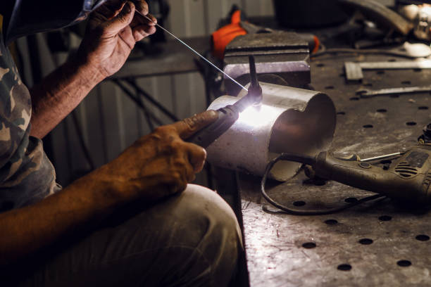 istock Industrial welder worker welding using argon machine, close up. Male in face mask welds with argon welding. 1708065996