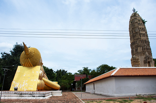 Ancient buddha reclining attitude statues and antique stupa ruins chedi of Wat Aranyikawat or Charoen Tham Wihan temple for thai people visit respect praying blessing wish holy in Ratchaburi, Thailand