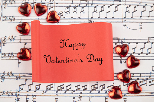Hearts  and red paper with text Happy Valentine's day, on musical score