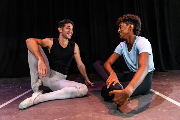Young ballet dancer men talking while taking a break at stage theater