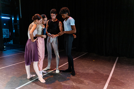 Young ballet dancers using mobile phone at stage theater