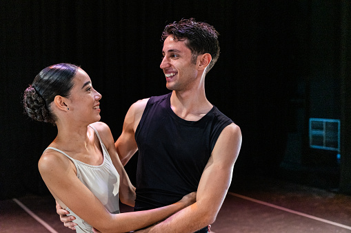 Young ballet friends embracing at stage theater