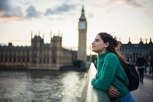 Young female tourist admiring the beauty of city of London on the Westminster bridge next to Big Ben.London,UK.