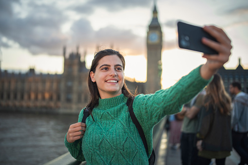 Happy young woman on vacation in London,Uk taking a selfie with the Big Ben monument.
