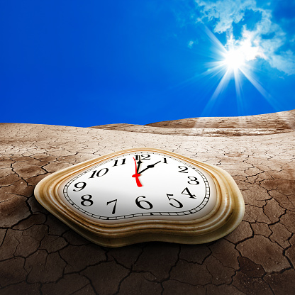 Conceptual melted clock face on dried landscape