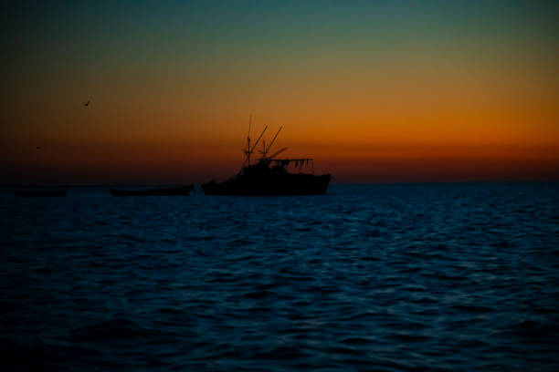 Fishing boat at sea at sunset