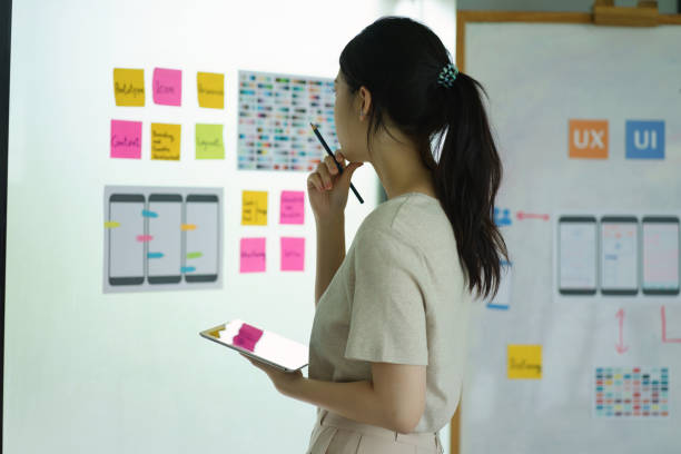 Creative ux designer brainstorming designing screens for mobile responsive website development with UI UX. Developing wireframe sketch layout design mockup on smartphone screen.