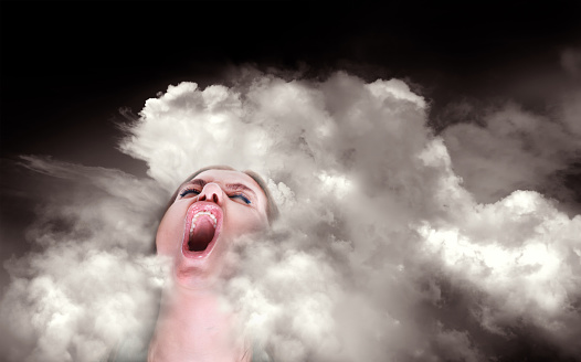 Portrait of close up mid adult woman screaming in dramatic storm clouds