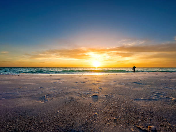 istock Silhouetted single man walking on tropical beach during colorful sunset 1708157174