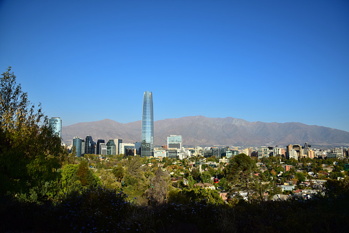 Viewed from San Cristobal Hill, a cable car moves across the cityscape with South America's tallest building, the Gran Torre Santiago, in the background.