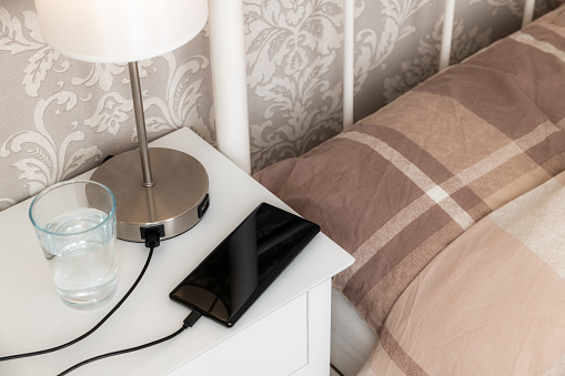 Smartphone charging on a bedside table, blank screen