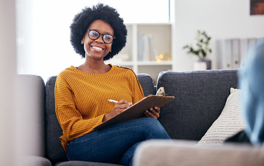 Black woman therapist on sofa with notes, smile and patient for advice and psychology, listening and mental health care help. Conversation, support and psychologist on couch with client in counseling