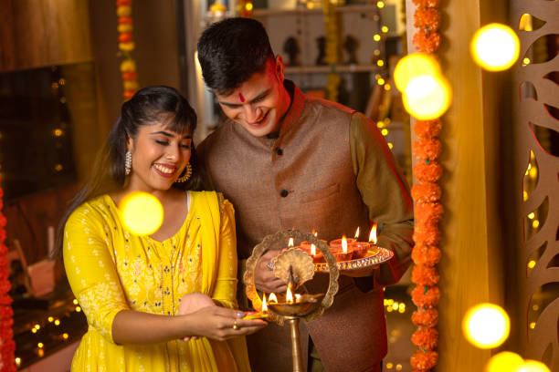 istock Happy couple lighting diyas at home during Diwali 1708257372