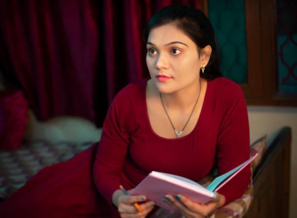istock Indian young woman holding a book and contemplating with a blank expression. 1708259229