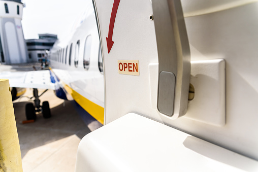 Open door of a plane parked while passengers disembark.