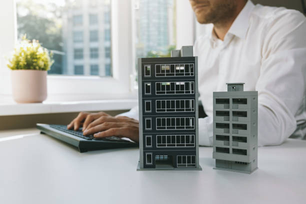 istock real estate business and development. businessman, developer or architect working in office, typing on computer keyboard. new apartment building scale models on the table 1708261846