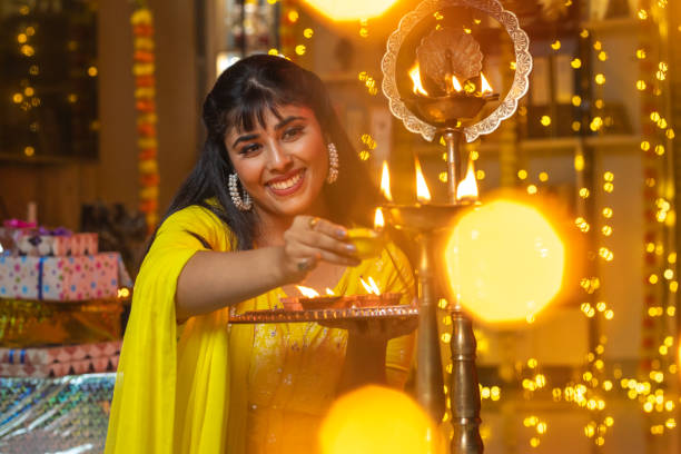 istock Happy woman lighting diyas at home during Diwali 1708268470