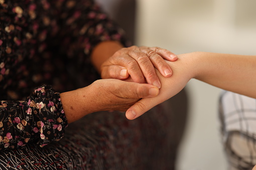 Young woman is holding a senior woman's  hand for help.