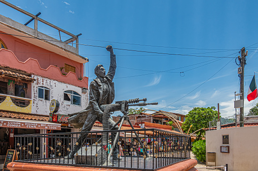 Zihuatanejo, Mexico - July 18, 2023: Corner closeup on Bronze Jose Azueta Abad statue in front of shopping street, Mexican Navy war hero during US occupation of Veracruz. Blue cloudscape