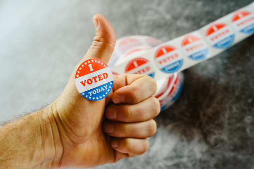 Man's hand teaching that he has voted today in the American elections with a sticker.