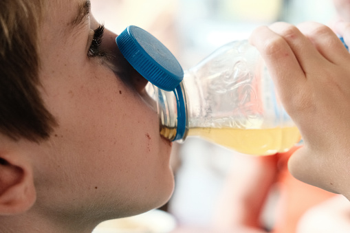 Child drinking a soft drink straight from a plastic bottle. Short shot. Detail